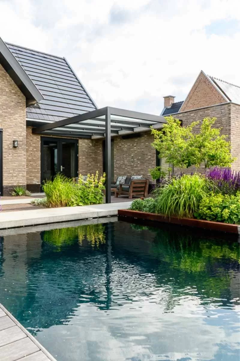 Zwemvijver met donkere waterkleur, Schellevisrand en moderne overkapping in luxe tuin